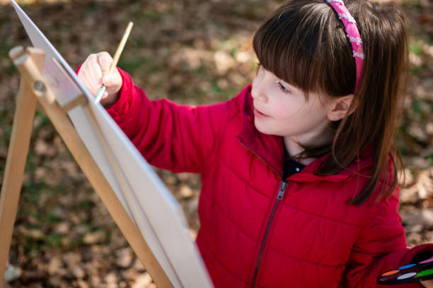 istock Little girl painting on easel 1744059413