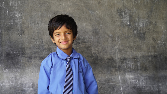 Indian school boy standing against blank chalkboard, intelligent and smart student, Education concept or Back to School