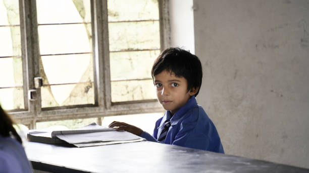 Portrait of happy indian school child sitting at desk in classroom, school kids with pens and notebooks writing test Elementary school, Education concept.