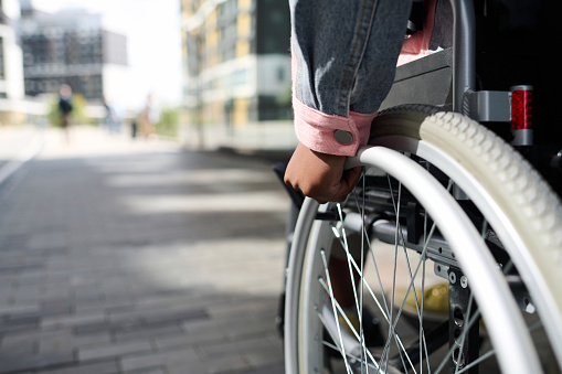 Close-up of woman with disability moving in wheelchair along the street