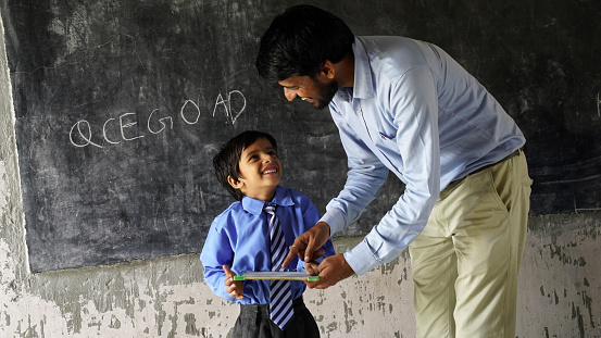 Indian teacher teaching to rural school student in classroom, Typical scene in a rural or small village school in India
