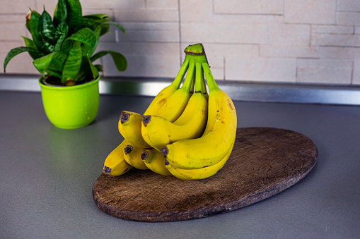 bunch of bananas on the table in the kitchen next to a home flower