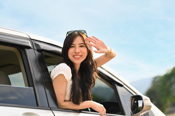 Relaxed young woman leaning out from car window on summer road trip. Journey, traveling, lifestyle concept stock photo