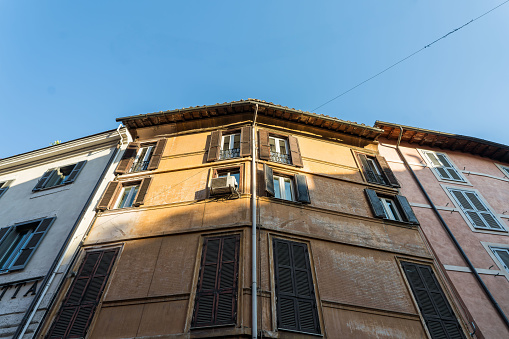 Looking up at a slither of the Setting sun catching the top of ancient Italian apartment blocks in Rome, Italy