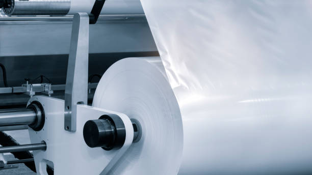 istock Automatic industrial machine for plastic packaging with light effect of products and food. shaft of an automated packaging line with plastic film in a light blue scene. product packaging concept 1744167005