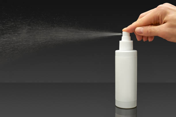 istock Human hand and  White cosmetic bottle spraying liquid, on black background 1744170769