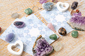 Deck with homemade fortune telling Angel cards on bright wooden table, surrounded with semi precious stones crystals for decoration.