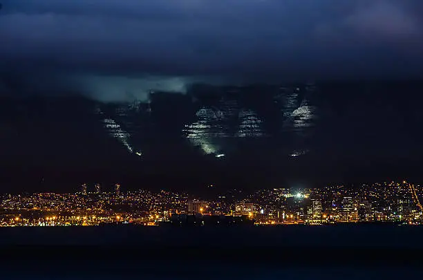 Night view of the City Bowl in Cape Town showing Table Mountain lit up and under its Table Cloth (The Cloud Cover)