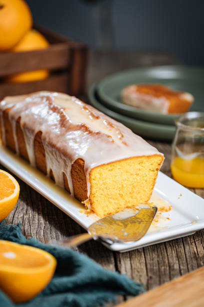 istock Popular sponge dessert called Pound cake with white glazing, served with oranges on rustic wooden background 1744194461