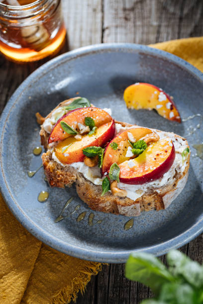 istock Spread with cream cheese on bread with rucola, nuts and peach. Healthy summer brunch. Vitamins and minerals 1744195582