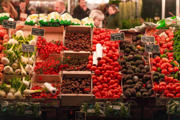 Front on People browse produce at outside grocery market, TorvehallerneKBH, in Copenhagen, Denmark