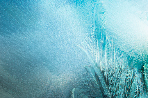 Melting ice running down a window pane, Closeup of frozen window pane surface with ice crystals