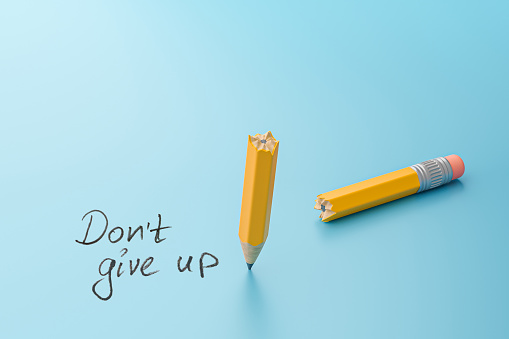 Don't give up. Broken pencil in half on a blue background.