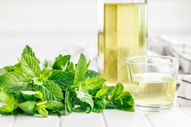 istock Sweet mint syrup and mint leaves on white table. 1744229045