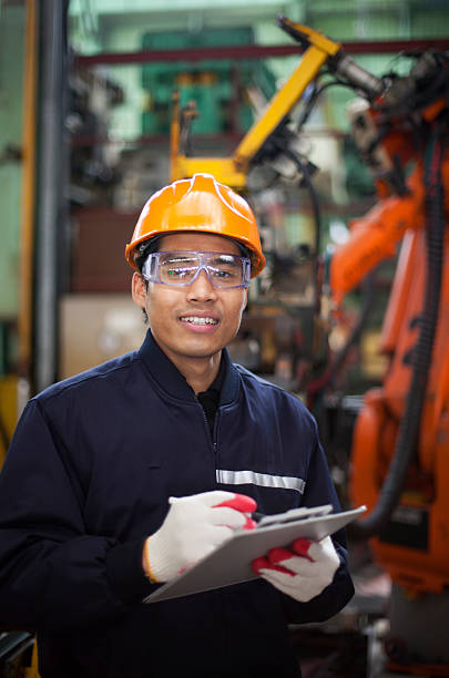 istock Young man in hard hat writing on clipboard in factory 174423553