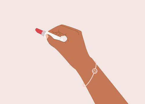 Black Female’s Hand Holding A Red Color Lipstick. Isolated On Color Background.