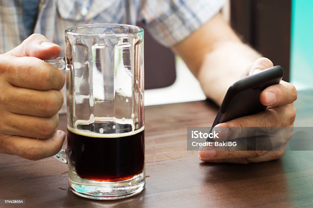 In the pub Close-up of male hands with mug of beer and smart phone. Active Seniors Stock Photo