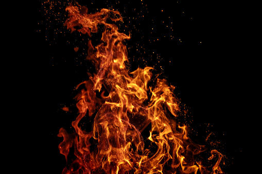 Burning fire with sparks on black background. Can be used as design element in screen add mode or as a text / product placement background.