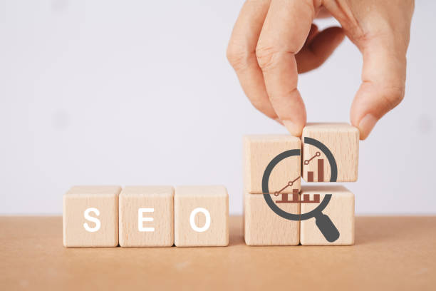 istock SEO, Search Engine Optimization ranking concept. Digital marketing strategy of promote traffic to website. Hand holds wooden cubes with the icon of magnifying glass with alphabets abbreviation SEO 1744301740