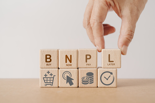 Hand arranged wooden cube blocks with  BNPL, alphabets abbreviation , and icon. For buy now pay later online shopping concept