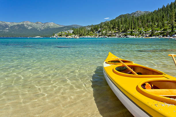 Yellow tandem empty kayak on clear water near trees