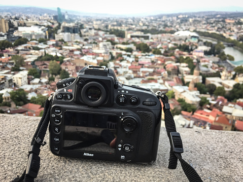 Tbilisi, Georgia - Sep 22, 2018. DSLR camera on the deck with Tbilisi cityscape background. Tbilisi is the capital and the largest city of Georgia.