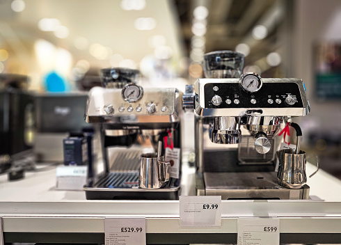 Modern coffee machines on display and for sale in the department store. Focus on the machines with the store defocused beyond.