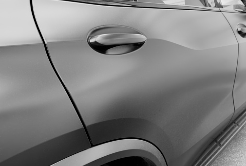 The modern door handle of a black car. Car exterior details. Closeup Car door handle