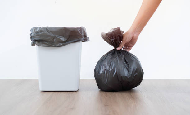 istock Housewife hand wearing  holding garbage bag in a kitchen with white wall background. 1744356327