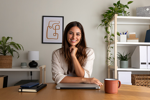 Young female entrepreneur at home office. Woman looking at camera sitting at desk.Working at home concept.