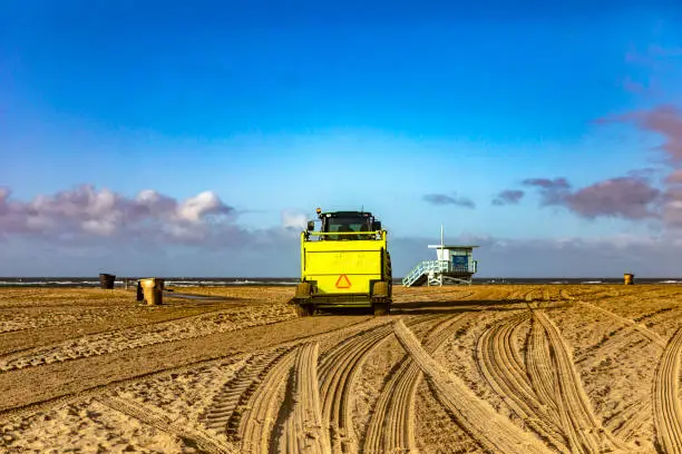 Photo of Photograph of a tractor arranging and tilling the sand on the beach in the city of Santa Monica in the state of California in the United States of America.