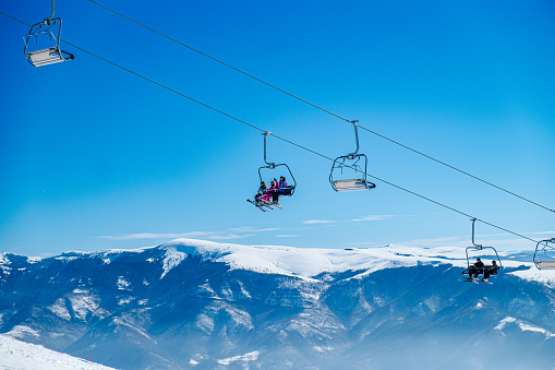 Ski lifts moving above the snowcapped mountain peaks and slopes on a beautiful clear day