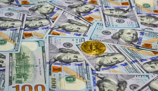Saigon, Vietnam - Jan 17, 2020. Golden bitcoin on USD 100 billnote dollar background.