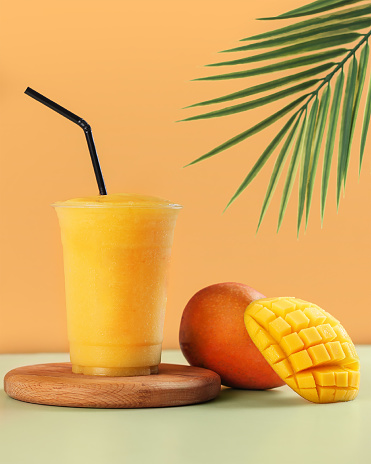 Fresh Mango Juice in wood podium with piece of mango