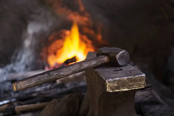 Hammer on anvil with fire in the background.