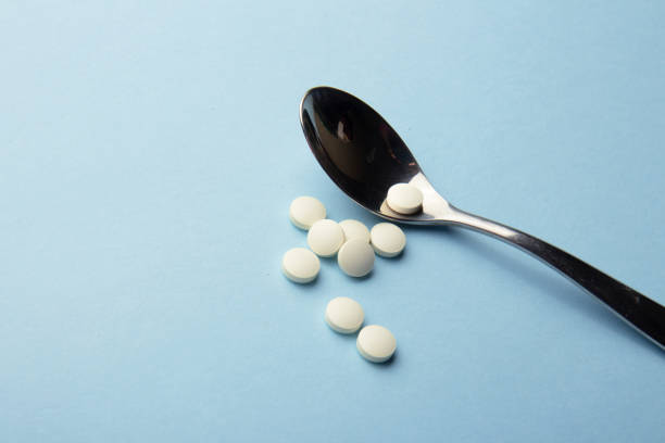 istock Dietary supplements. White vitamin tablets on iron spoon on a blue background 1744435971