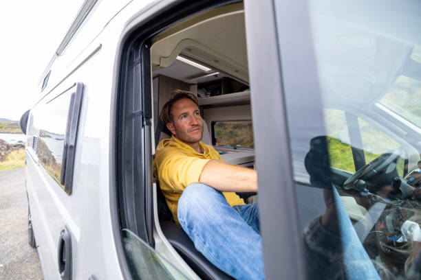 istock Man on a road trip with his camper van, he looks through window 1744442329