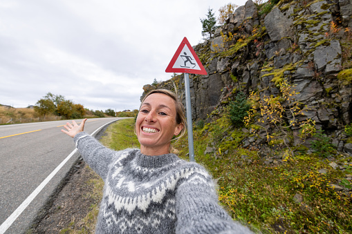 Funny selfie of woman posing with moose crossing warning sign