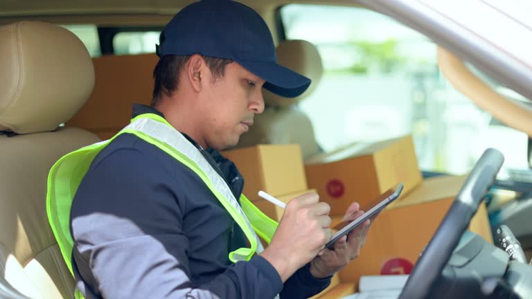 Delivery man takes out box parcel from a cargo van and goes to the house to deliver the package to the homeowner