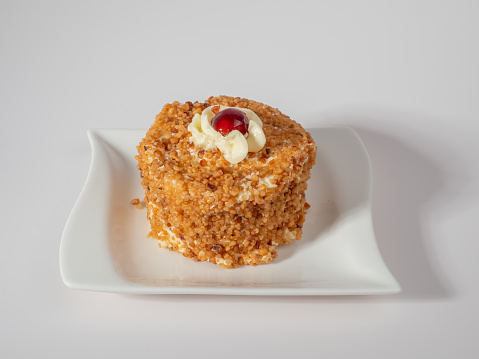 Butter cake with cherry filling on a bright white background. Butter cake decorated with juicy cherries. A delicious butter cake topped with a single cherry on a white surface.