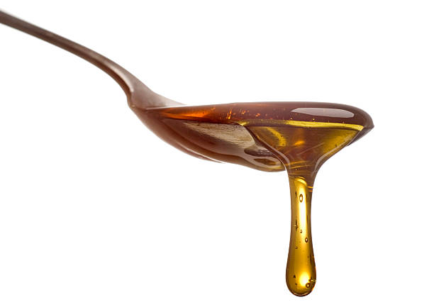 A spoon with dripping English Golden Sirup, isolated on white