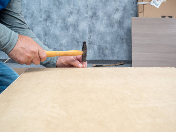 um homem está fazendo um trabalho de montagem de móveis. - wood laminate flooring floor nail hammer - fotografias e filmes do acervo