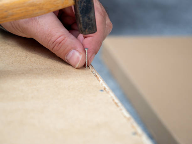 um homem está fazendo um trabalho de montagem de móveis. - wood laminate flooring floor nail hammer - fotografias e filmes do acervo