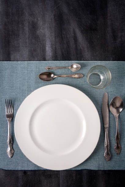 istock Plates, cutlery and tablecloth on black table top view. 1744479635