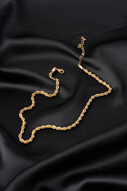 istock Gold chain on black silk fabric background 1744482069