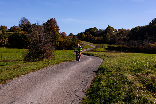 Skocjanske Park, Slovenia - November 01, 2022: Biking cyclist male athlete going uphill on open road training hard on bicycle outdoors. Slovenia