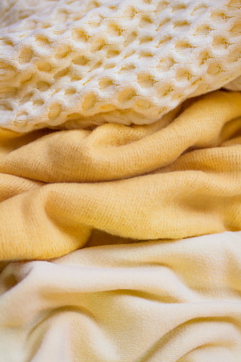 Close up of a pastel yellow knitted fabrics. Textured abstract pattern as background.