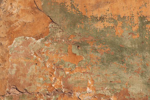 An old pitted and weathered rusty metal sheet background framed by old rusty bolts. Lots of texture with subtle abstract colors of the patina.