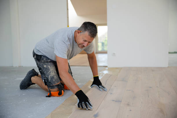 middle-aged man with gray hair glues, lays parquet floor - empreiteiro de reparações imagens e fotografias de stock