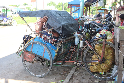 Brebes-Indonesia, 27 January 2020. A rickshaw puller is sitting in a rickshaw.